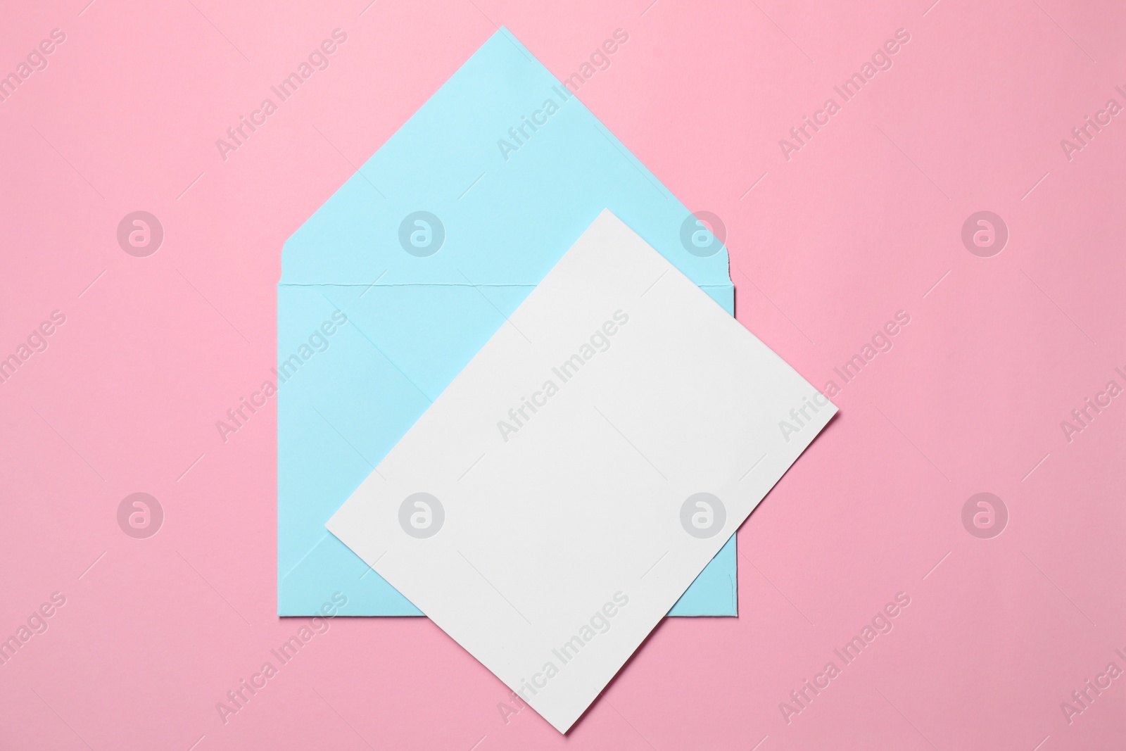 Photo of Letter envelope and card on pink background, top view