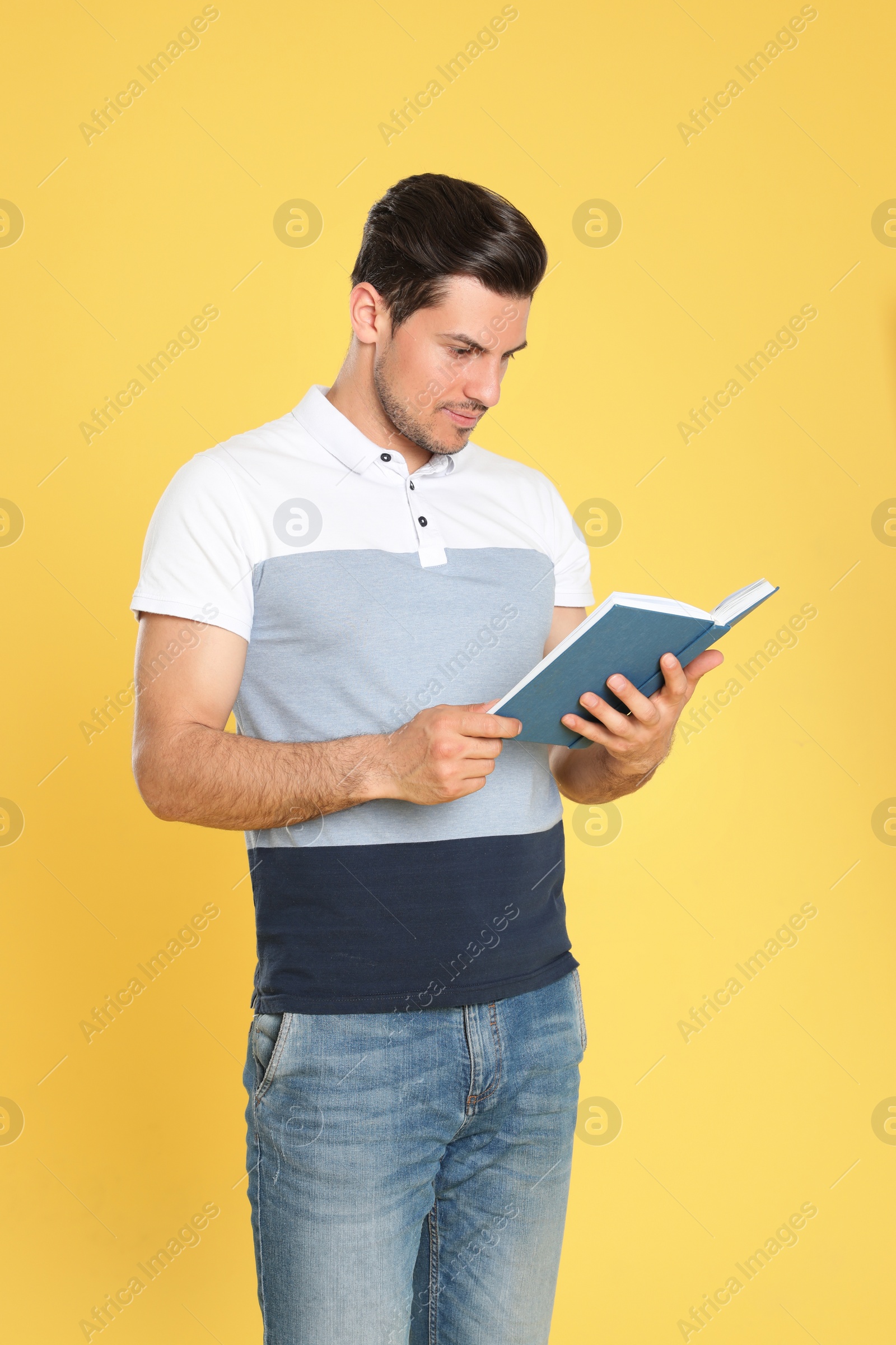 Photo of Handsome man reading book on color background