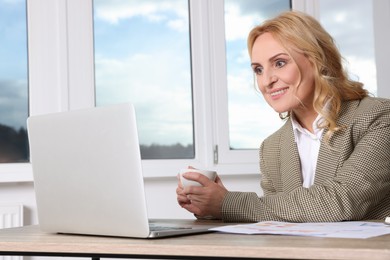 Lady boss working on laptop at desk in office. Successful businesswoman