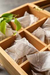 Paper tea bags in wooden box on table, closeup