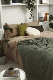 Comfortable bed and different houseplants in bedroom. Interior design