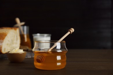 Photo of Jar with honey and butter on wooden table, space for text
