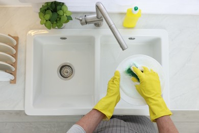 Photo of Man washing plate in kitchen sink, top view