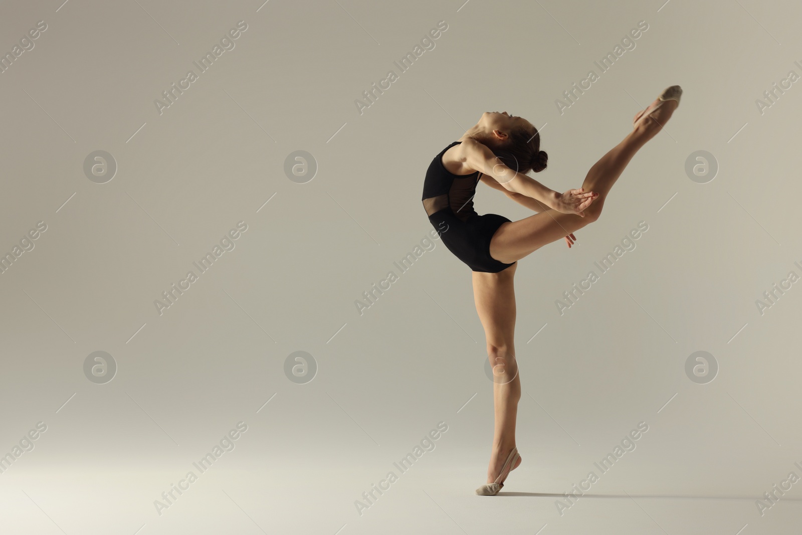 Photo of Cute little girl doing gymnastic exercise on white background