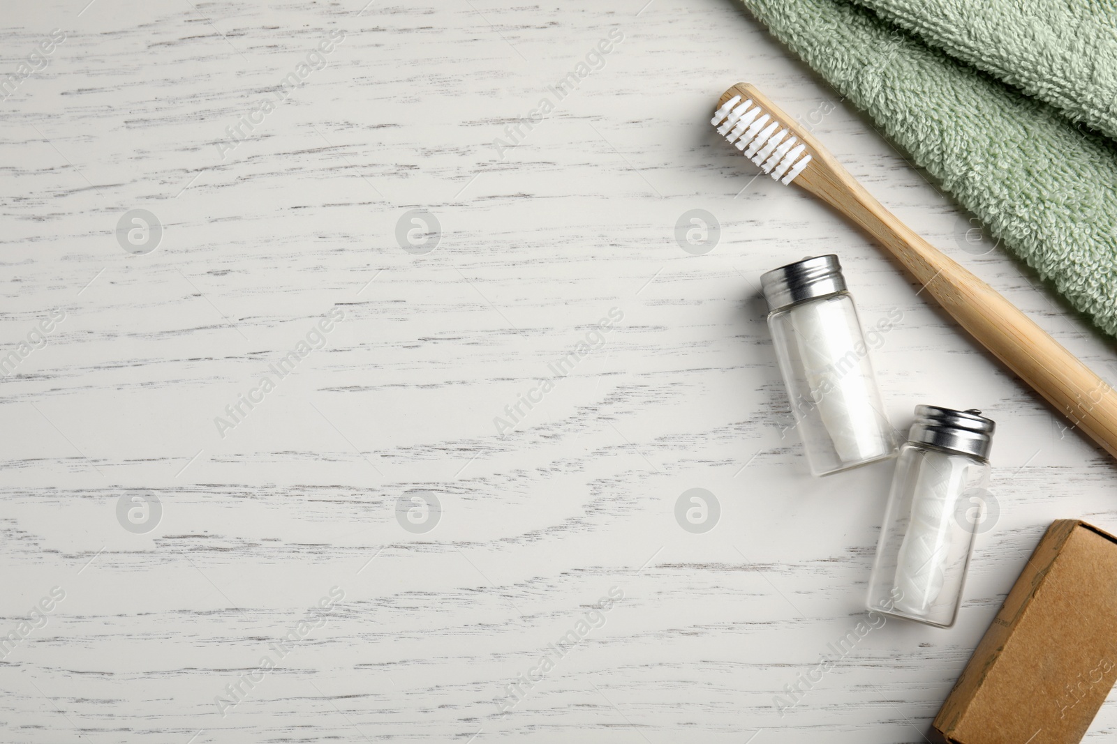 Photo of Flat lay composition with biodegradable dental flosses and bamboo toothbrush on white wooden table. Space for text