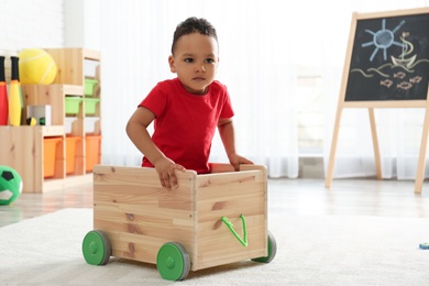 Photo of Cute little African-American child playing in kindergarten, space for text. Indoor activity