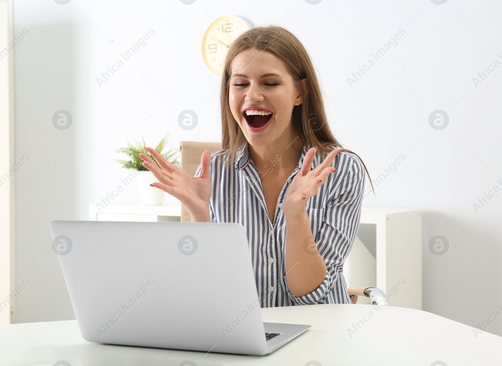Photo of Emotional young woman with laptop celebrating victory in office