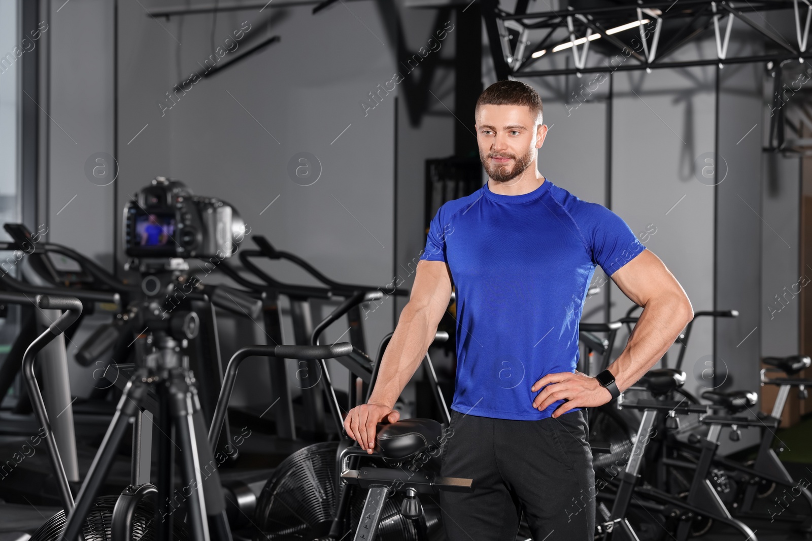 Photo of Man recording online training on camera at gym. Fitness coach