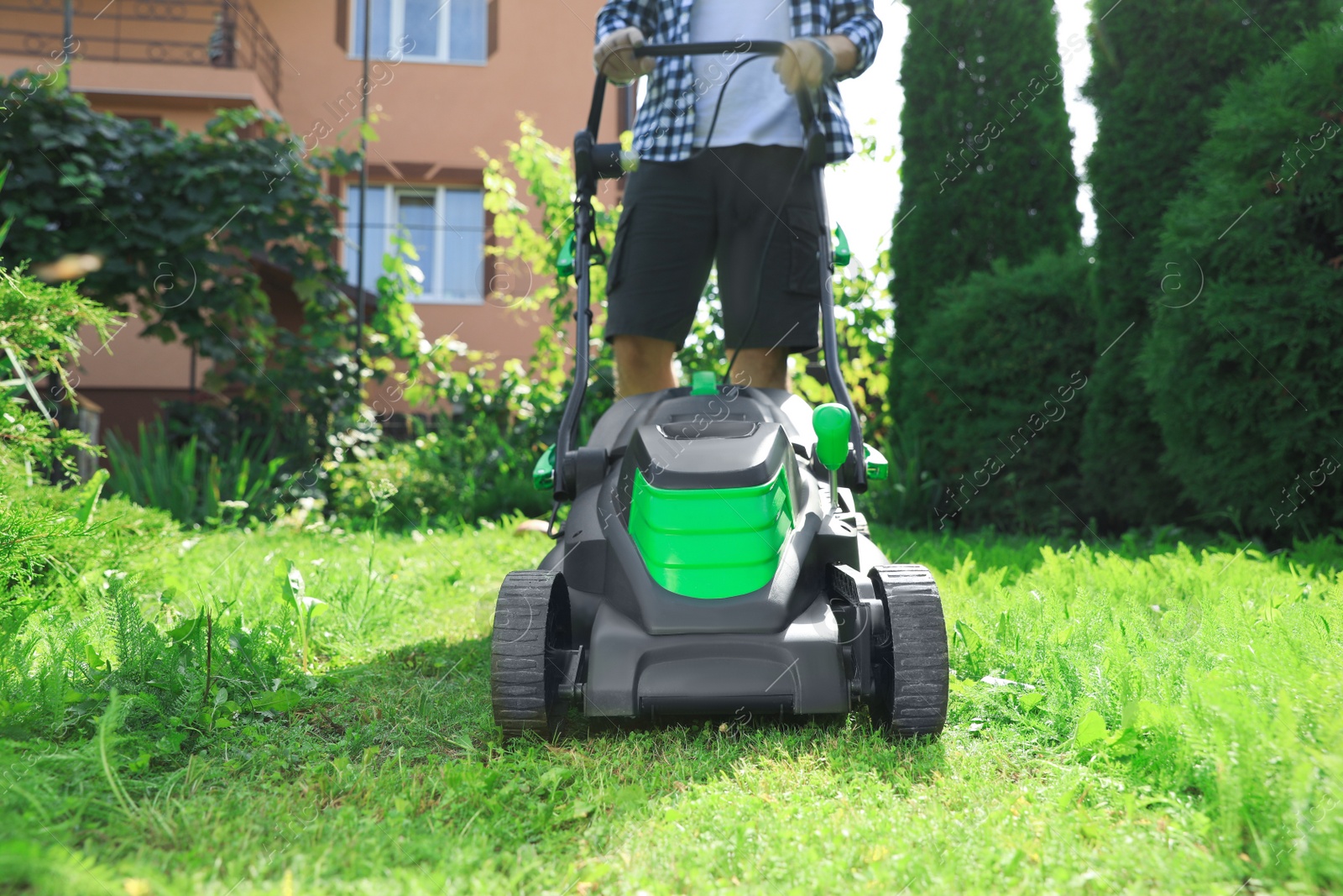 Photo of Man turning on lawn mower in garden, closeup. Cutting grass