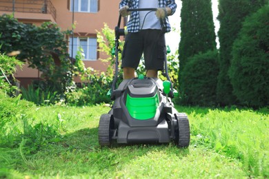 Man turning on lawn mower in garden, closeup. Cutting grass