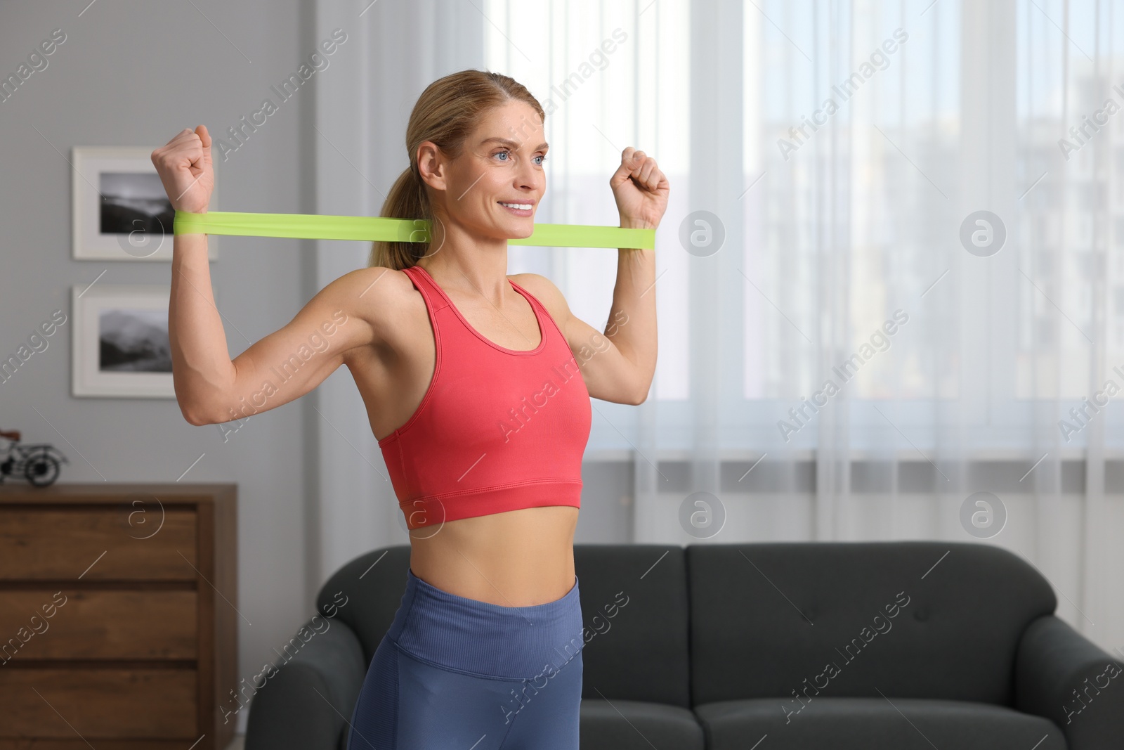 Photo of Athletic woman doing exercise with fitness elastic band at home. Space for text