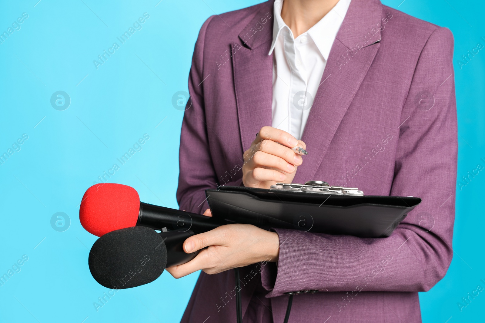 Photo of Professional journalist taking notes on light blue background, closeup