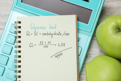 Notebook with calculated glycemic load for apples, calculator and fresh fruits on light wooden table, closeup