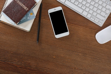 Flat lay composition with mobile phone and passport on wooden table, space for design. Travel agency concept