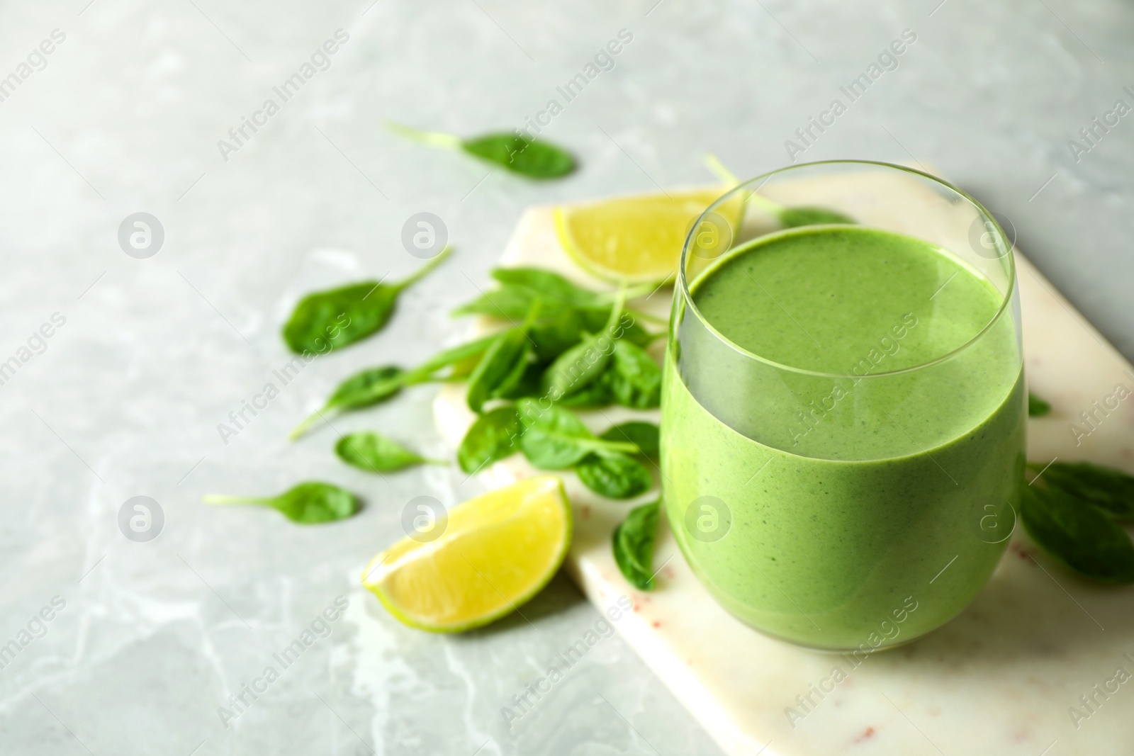 Photo of Glass of healthy green smoothie with fresh spinach on light table. Space for text