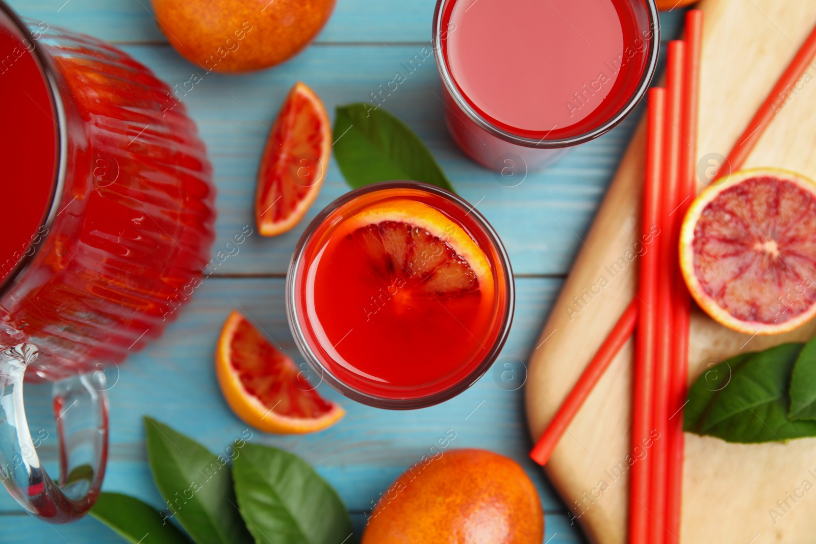 Photo of Tasty sicilian orange juice and fruits on light blue wooden table, flat lay