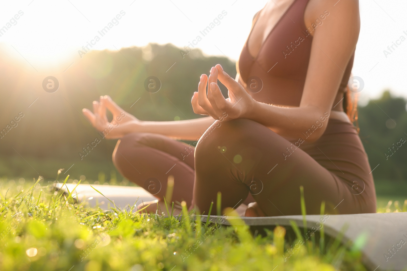 Photo of Woman practicing Padmasana on yoga mat outdoors, closeup and low angle view. Lotus pose