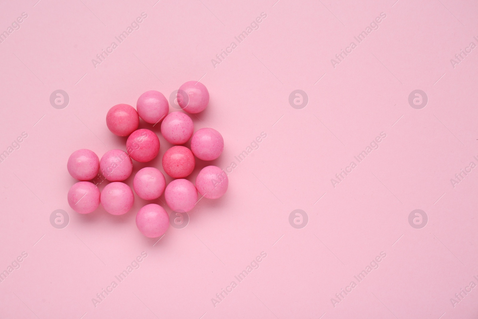 Photo of Many bright chewy gumballs on pink background, flat lay. Space for text