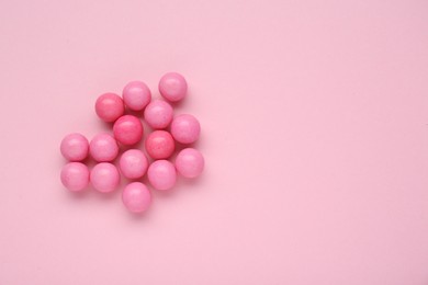 Photo of Many bright chewy gumballs on pink background, flat lay. Space for text