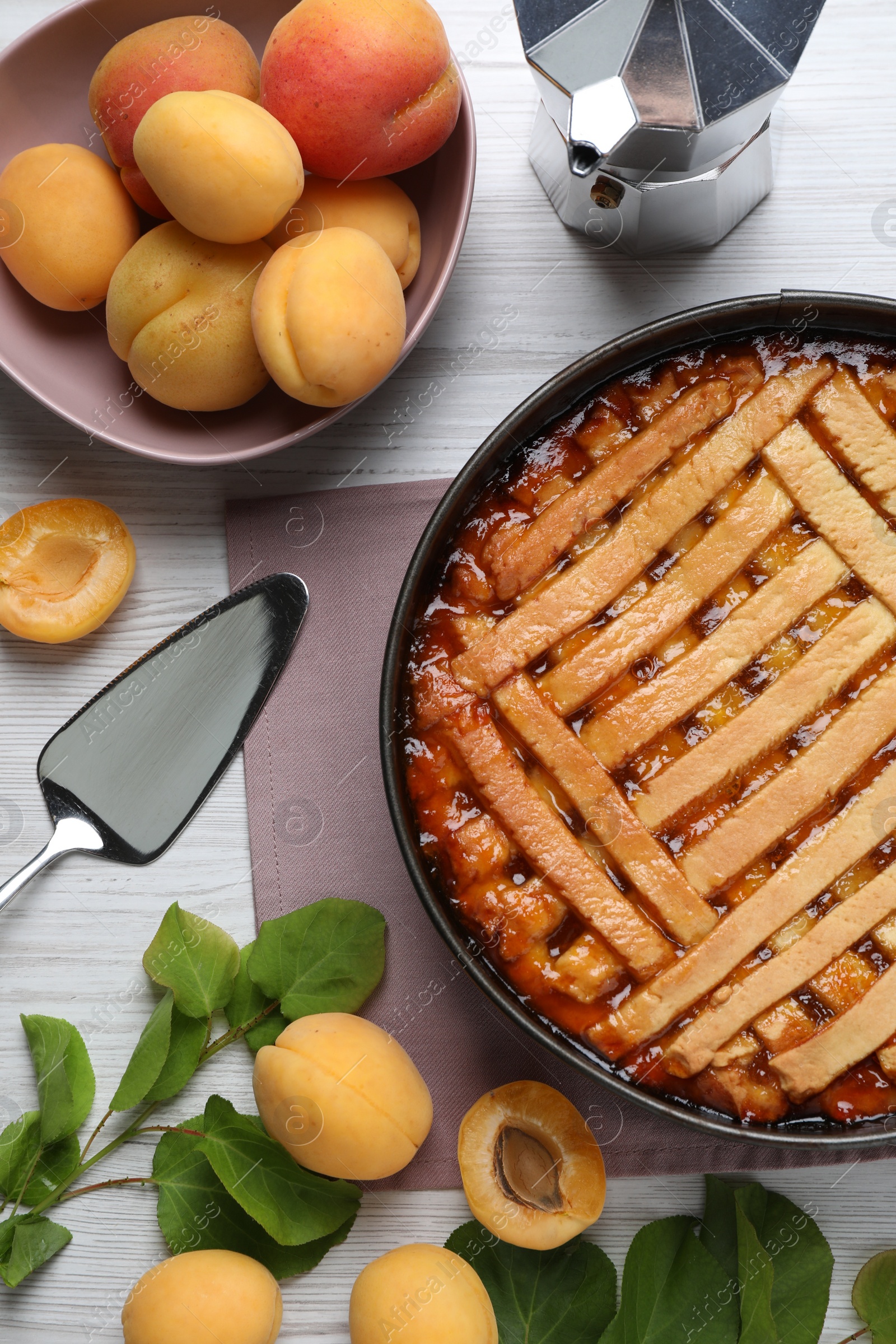 Photo of Delicious apricot pie in baking dish and fresh fruits on white wooden table, flat lay