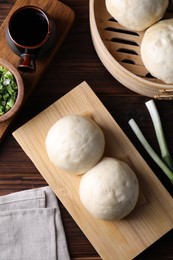 Photo of Delicious Chinese steamed buns, green onion and soy sauce on wooden table, flat lay