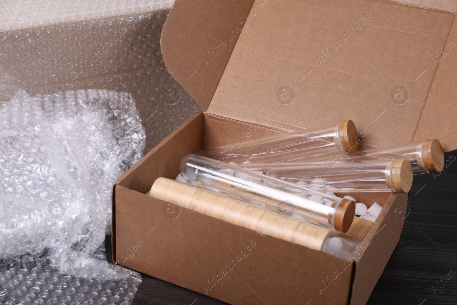 Photo of Test tubes in cardboard box and bubble wrap on dark wooden table