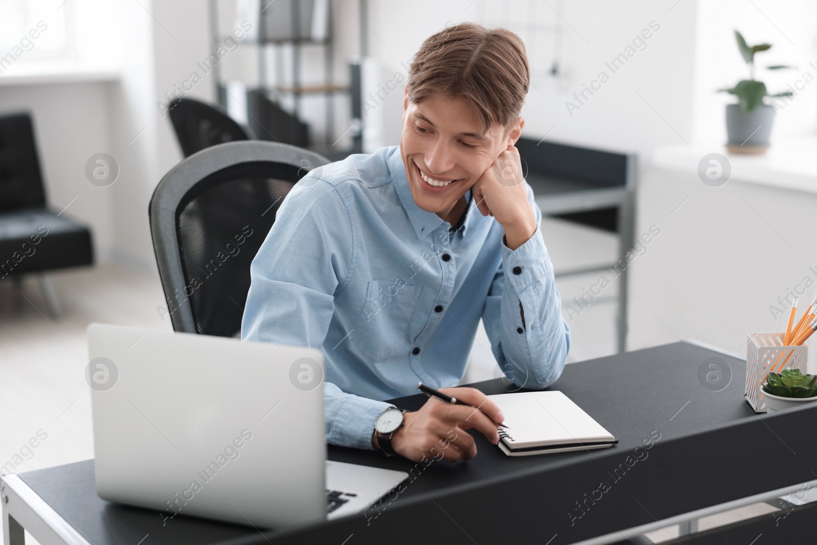 Photo of Man watching webinar at table in office