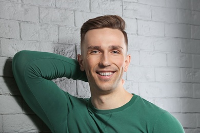 Photo of Portrait of young man with beautiful hair on brick wall background