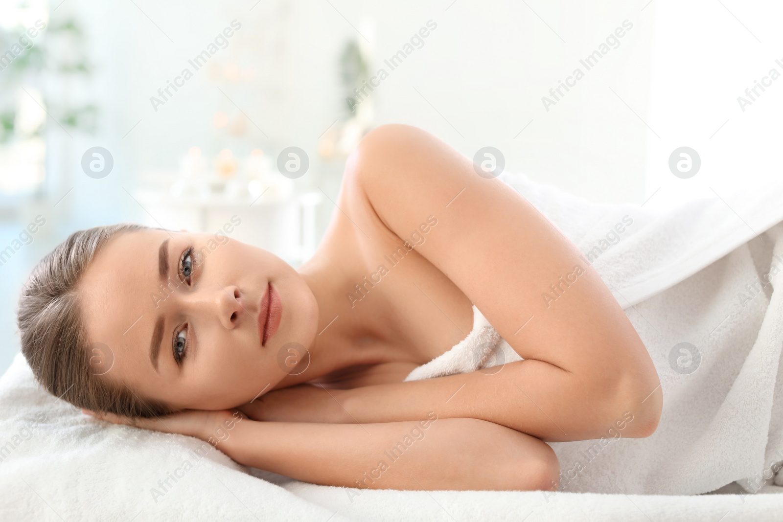 Photo of Young woman lying on massage table in spa salon