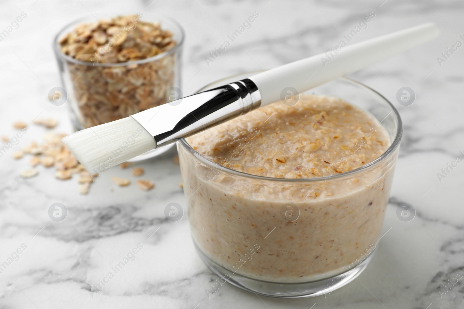 Photo of Handmade face mask made of oatmeal on white marble table