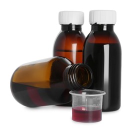 Photo of Bottles of cough syrup and measuring cup on white background