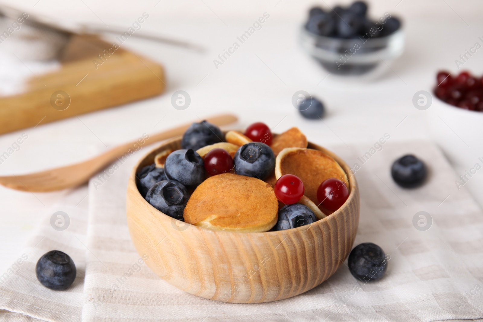 Photo of Delicious mini pancakes cereal with berries served on table