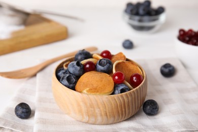 Photo of Delicious mini pancakes cereal with berries served on table