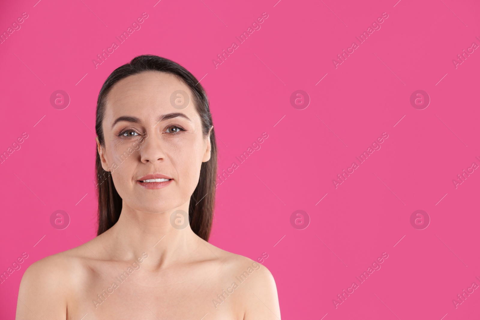 Photo of Portrait of beautiful mature woman on pink background. Space for text