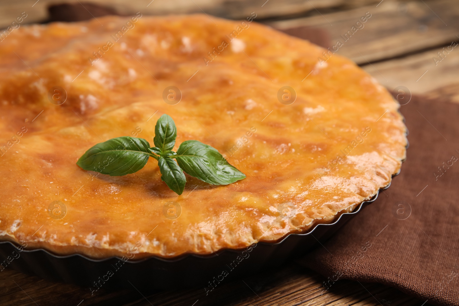 Photo of Delicious pie with meat and basil on wooden table, closeup