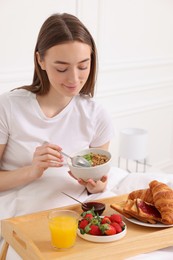 Photo of Beautiful woman having tasty breakfast in bed at home