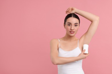 Beautiful woman applying deodorant on pink background, space for text