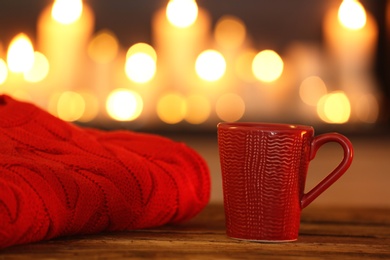 Cup of hot drink on wooden table against blurred background. Winter atmosphere