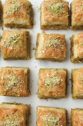 Photo of Delicious fresh baklava with chopped nuts on white table, flat lay. Eastern sweets