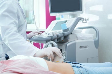 Doctor conducting ultrasound examination of internal organs in clinic, closeup