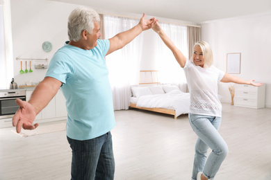 Happy mature couple dancing together at home