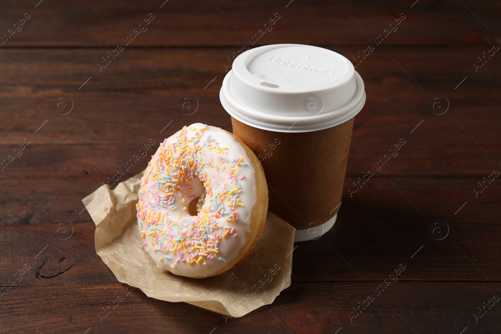 Photo of Yummy donut and paper cup on wooden table