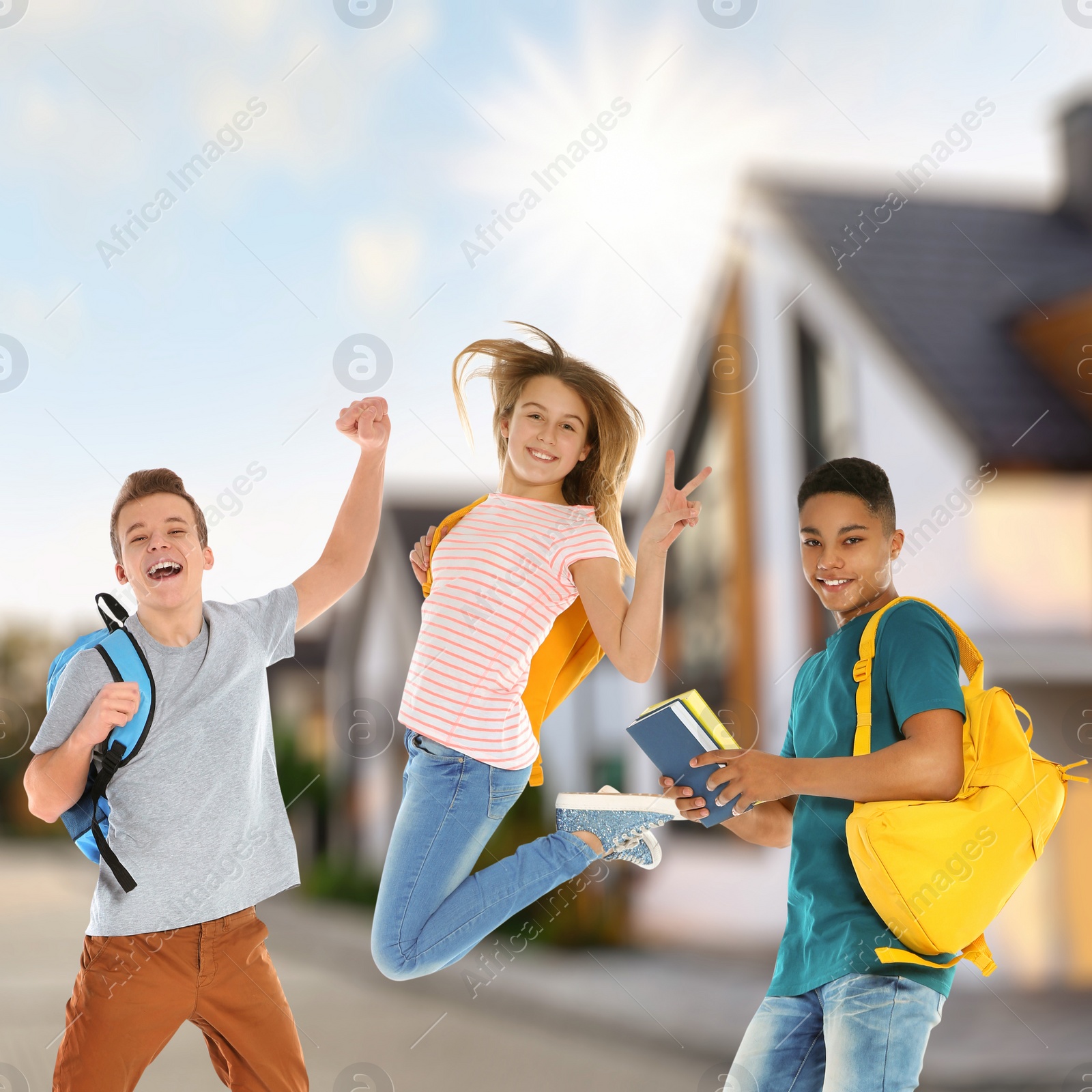 Image of Happy teenage girl jumping near classmates in front of house. School holidays