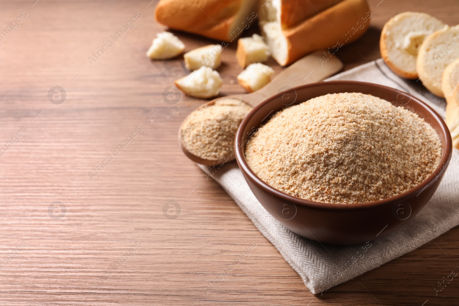 Photo of Fresh bread crumbs in bowl on wooden table, space for text