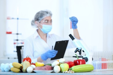 Photo of Fresh vegetables, fruits, meat on table and scientist proceeding quality control in laboratory