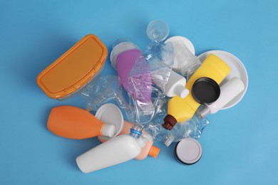 Pile of plastic garbage on light blue background, flat lay