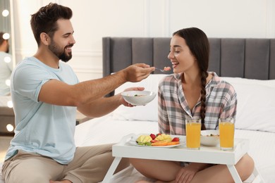 Photo of Happy couple having breakfast on bed at home