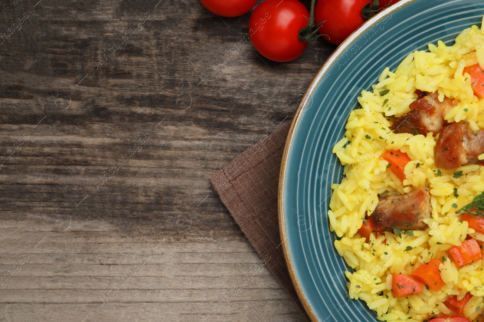 Photo of Delicious pilaf with meat and tomatoes on wooden table, flat lay. Space for text