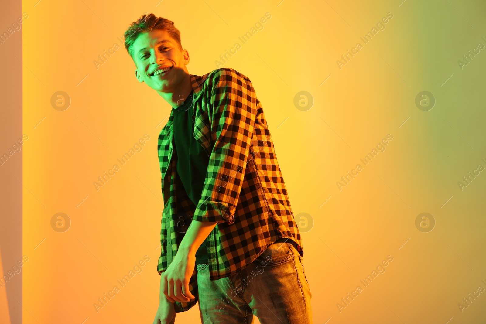 Photo of Young man dancing on color background in neon lights