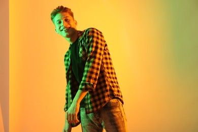 Photo of Young man dancing on color background in neon lights